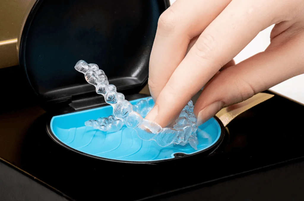 手從收納盒取出隱形牙箍的特寫畫面，2026 隱形牙箍全攻略：擔心牙齒不齊影響美觀？牙齒矯正必讀（含價錢參考、治療流程、清潔保養指南）專題配圖，展示隱形牙箍日常收納、清潔保養與護理細節